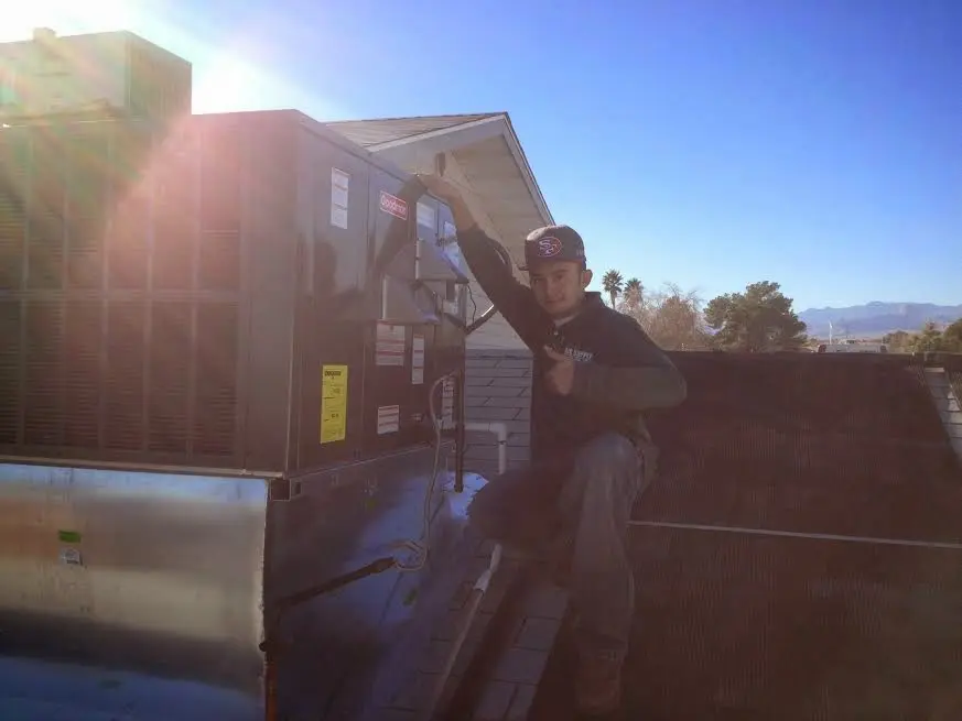 HVAC technician performing AC Tune-Up on a rooftop unit in Tecumseh